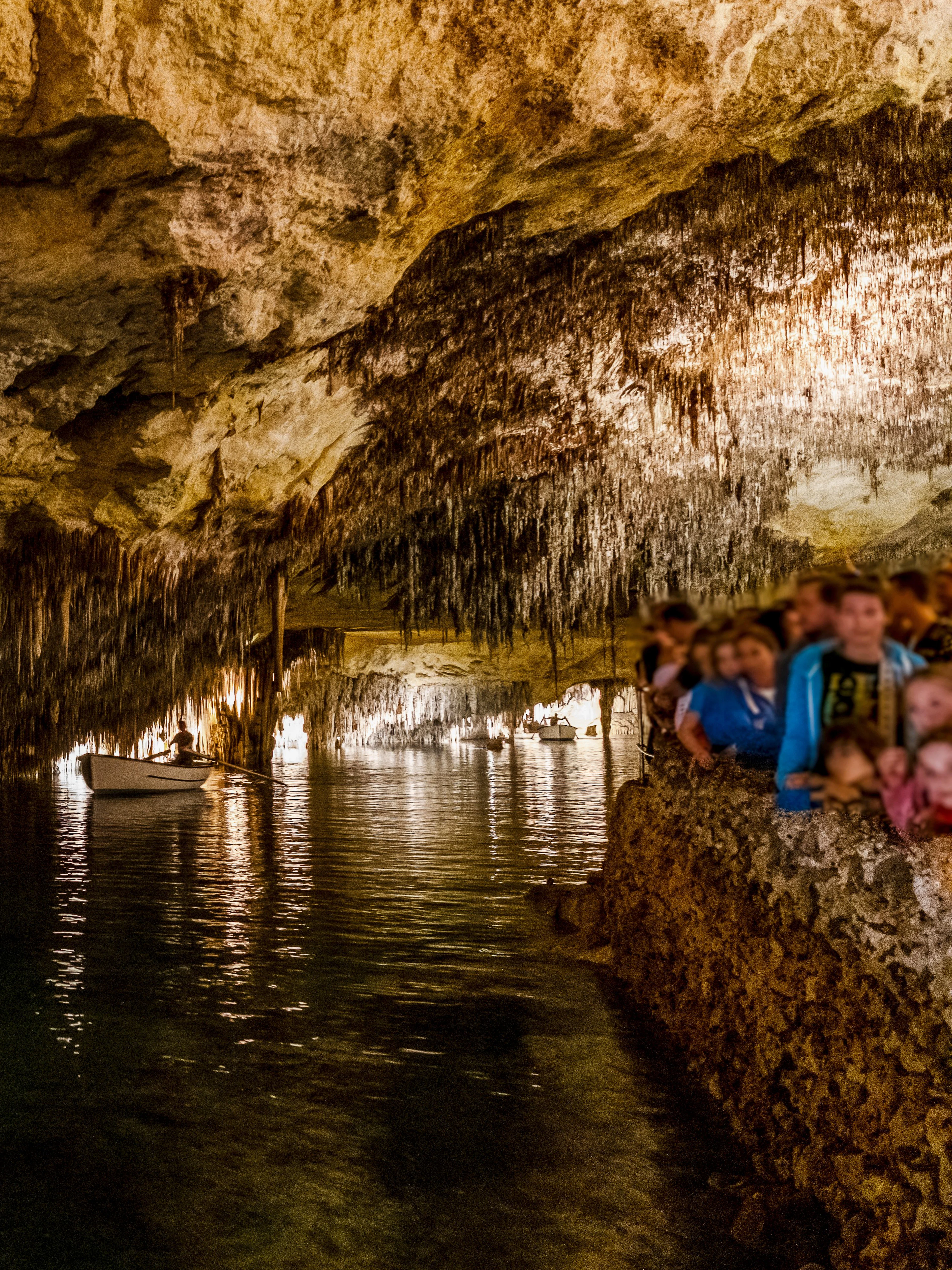 Boat tour inside Drach Caves, Mallorca, Spain with people exploring the illuminated cavern.