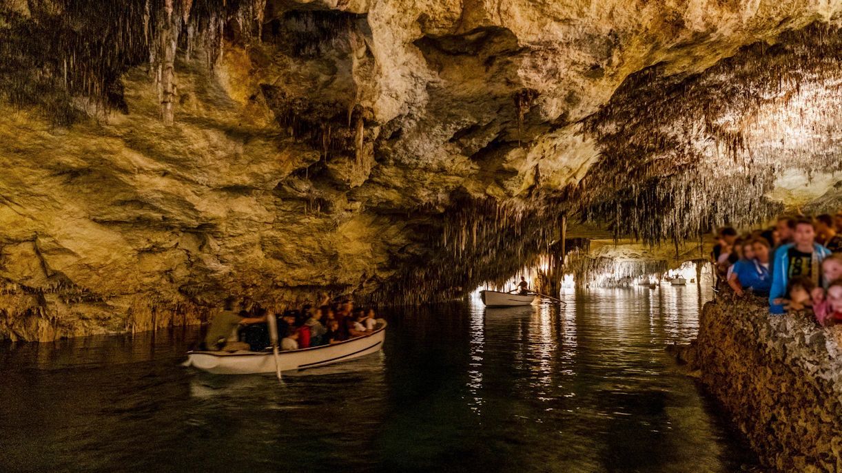 Boat tour inside Drach Caves, Mallorca, Spain with people exploring the illuminated cavern.