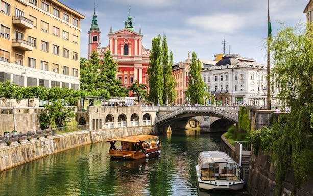 Boat on Ljubljanica River with view of Franciscan Church, Ljubljana, Slovenia.