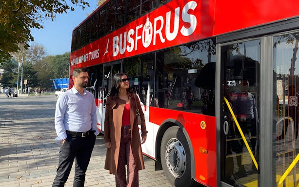 Istanbul tourists near hop-on-hop-off bus for city tour.