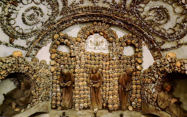 Capuchin Crypt in Rome Catacombs with monk statues and skull decorations.