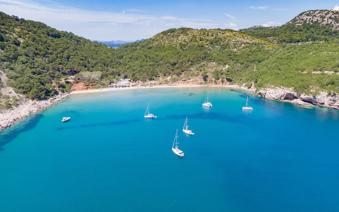 Sailboats anchored in a bay surrounded by lush hills on a Dubrovnik island-hopping cruise in the Elaphites.