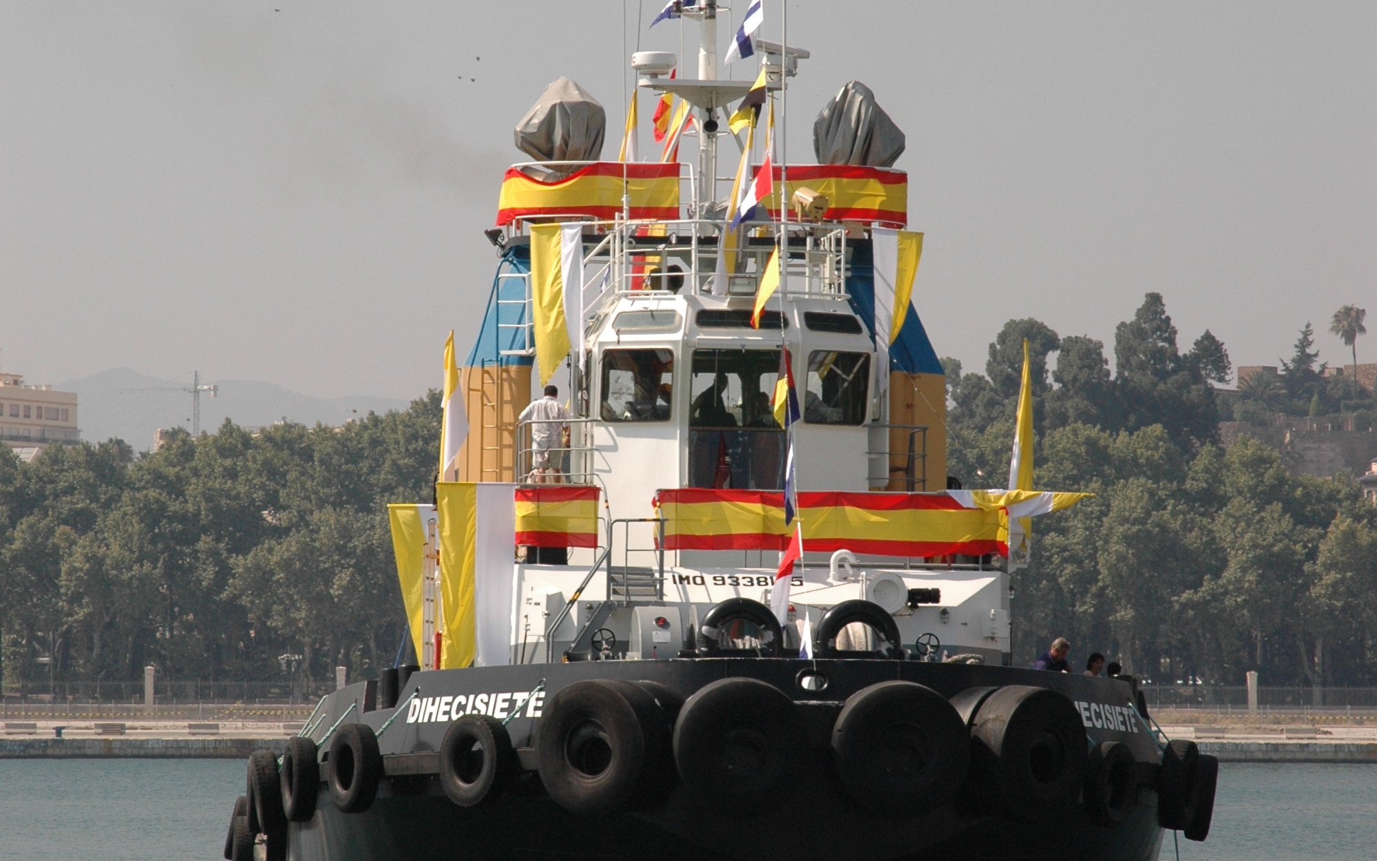 Decorated tugboat for Fiesta del Carmen with flags and banners in harbor.