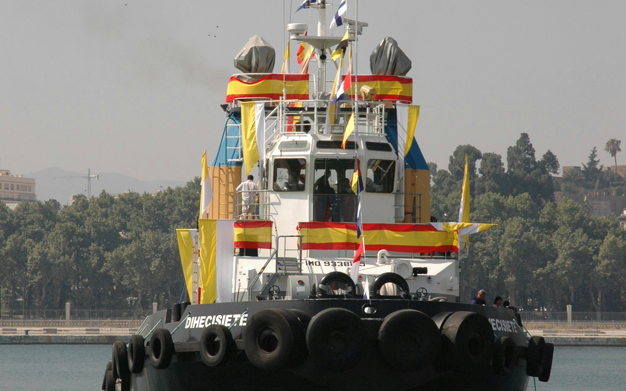 Decorated tugboat for Fiesta del Carmen with flags and banners in harbor.