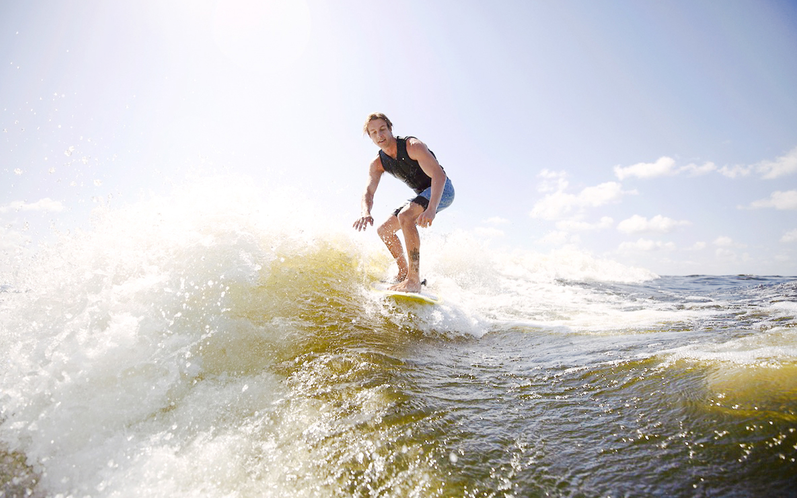 Man wakeboarding on waves in Dubai under a clear sky.