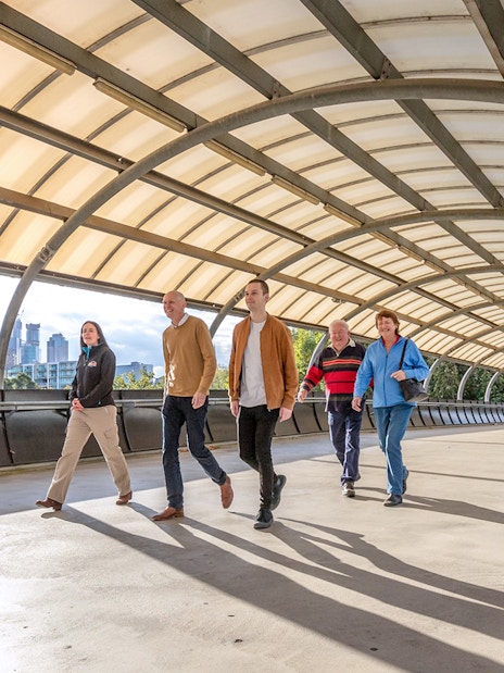 Group walking on a covered bridge with Melbourne skyline in the background.