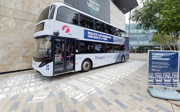 Electric bus at Glasgow airport terminal promoting eco-friendly city travel.