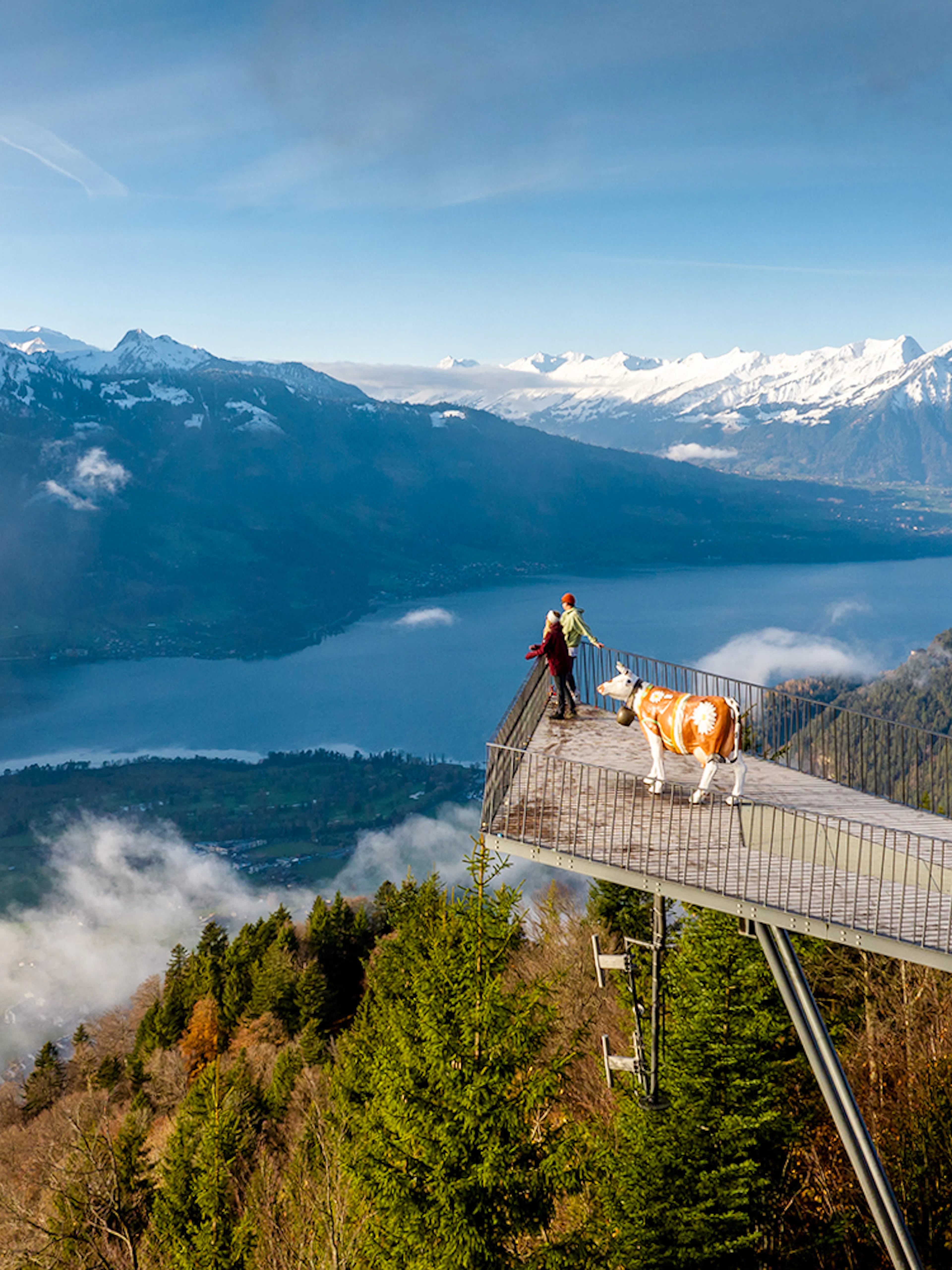 Couple at Two Lakes Bridge viewpoint, Harder Kulm, overlooking mountains and lake.