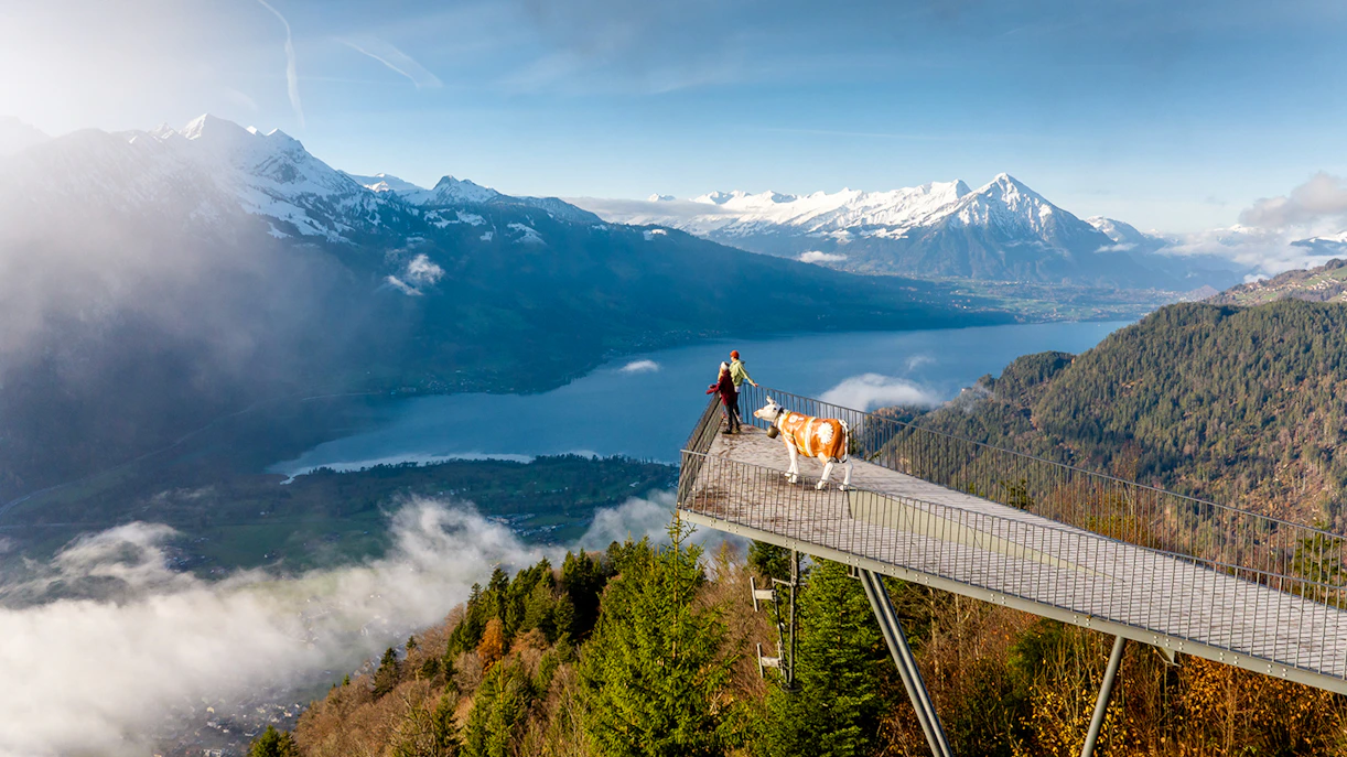Couple at Two Lakes Bridge viewpoint, Harder Kulm, overlooking mountains and lake.