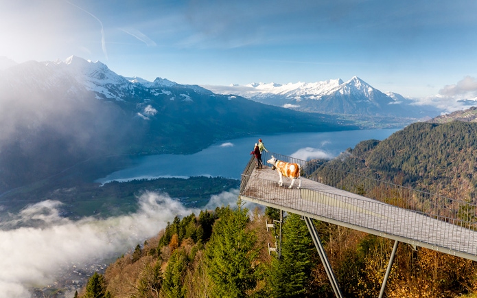 Couple at Two Lakes Bridge viewpoint, Harder Kulm, overlooking mountains and lake.
