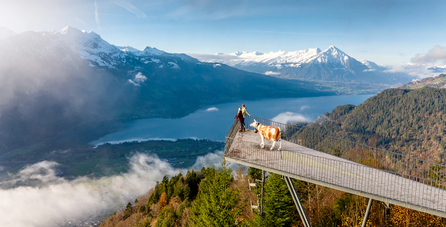 Couple at Two Lakes Bridge viewpoint, Harder Kulm, overlooking mountains and lake.