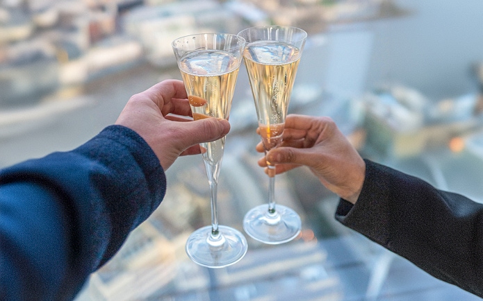 Toasting champagne glasses with a view from The Shard, London.