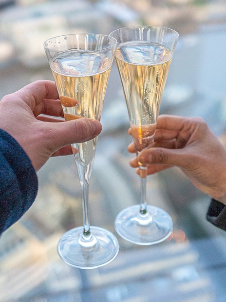 Toasting champagne glasses with a view from The Shard, London.