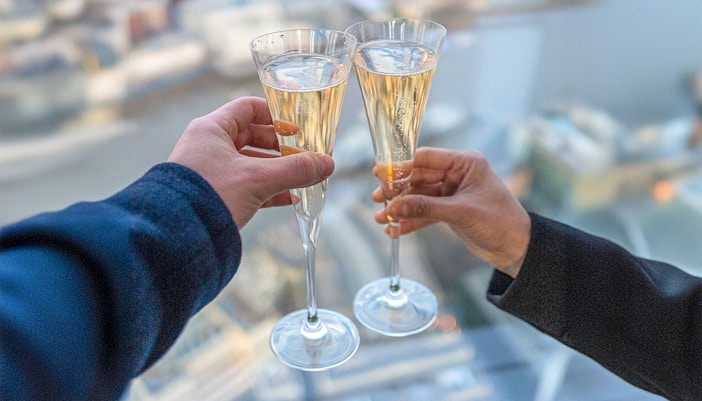 Toasting champagne glasses with a view from The Shard, London.