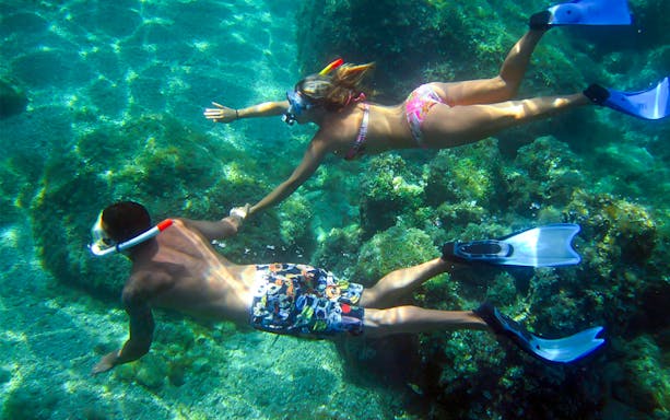 Couple snorkeling over coral reefs in Tavora Island.