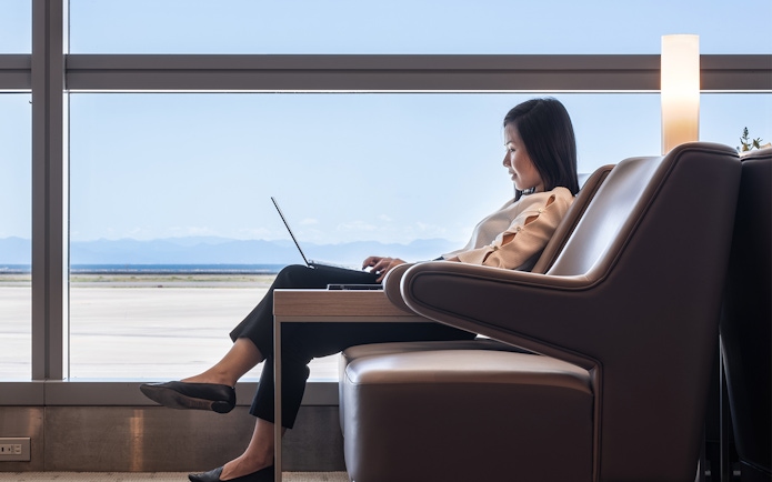 Person working on a laptop in Plaza Premium Lounge at Chubu Centrair Airport.