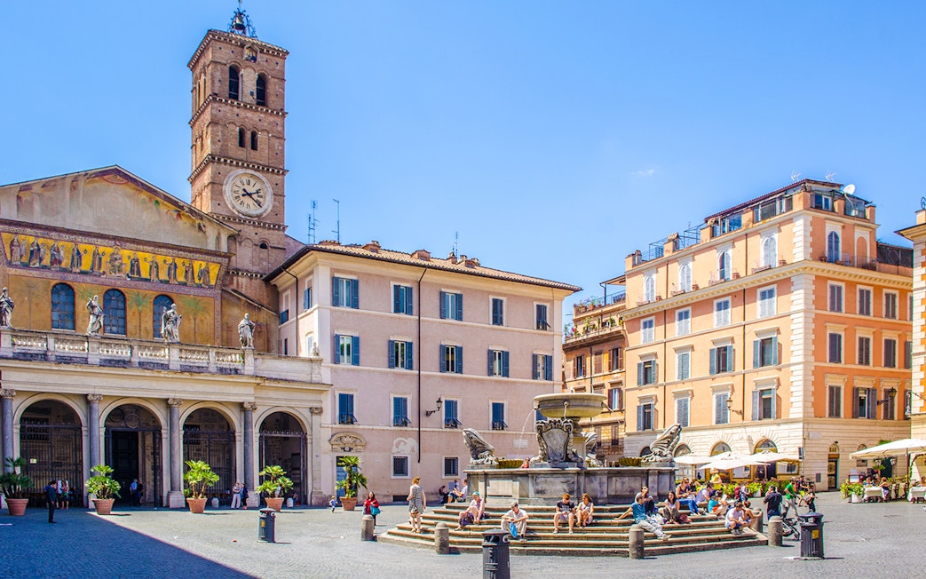 People strolling in Piazza di Santa Maria, Trastevere, Rome, near the basilica and fountain.