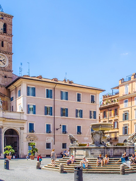 People strolling in Piazza di Santa Maria, Trastevere, Rome, near the basilica and fountain.