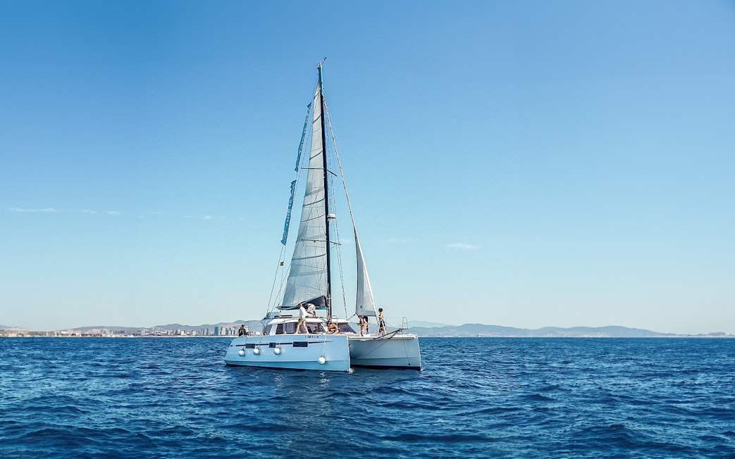 Eco-catamaran sailing near Barcelona coastline.