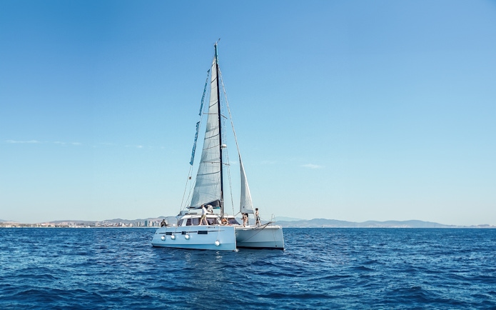 Eco-catamaran sailing near Barcelona coastline.