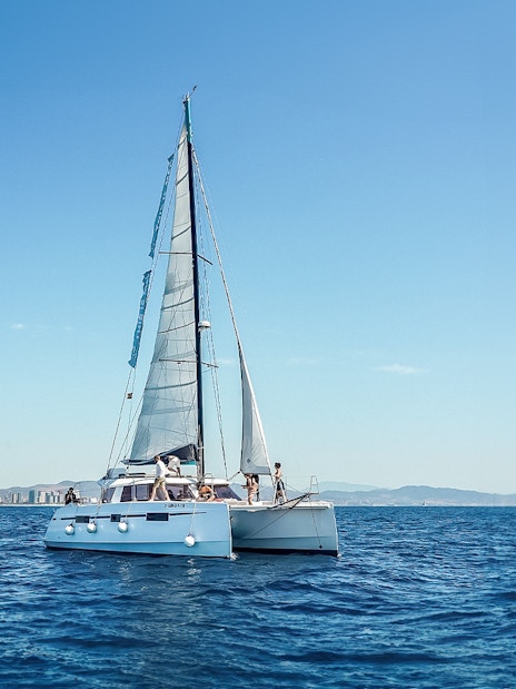 Eco-catamaran sailing near Barcelona coastline.
