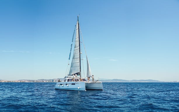 Eco-catamaran sailing near Barcelona coastline.
