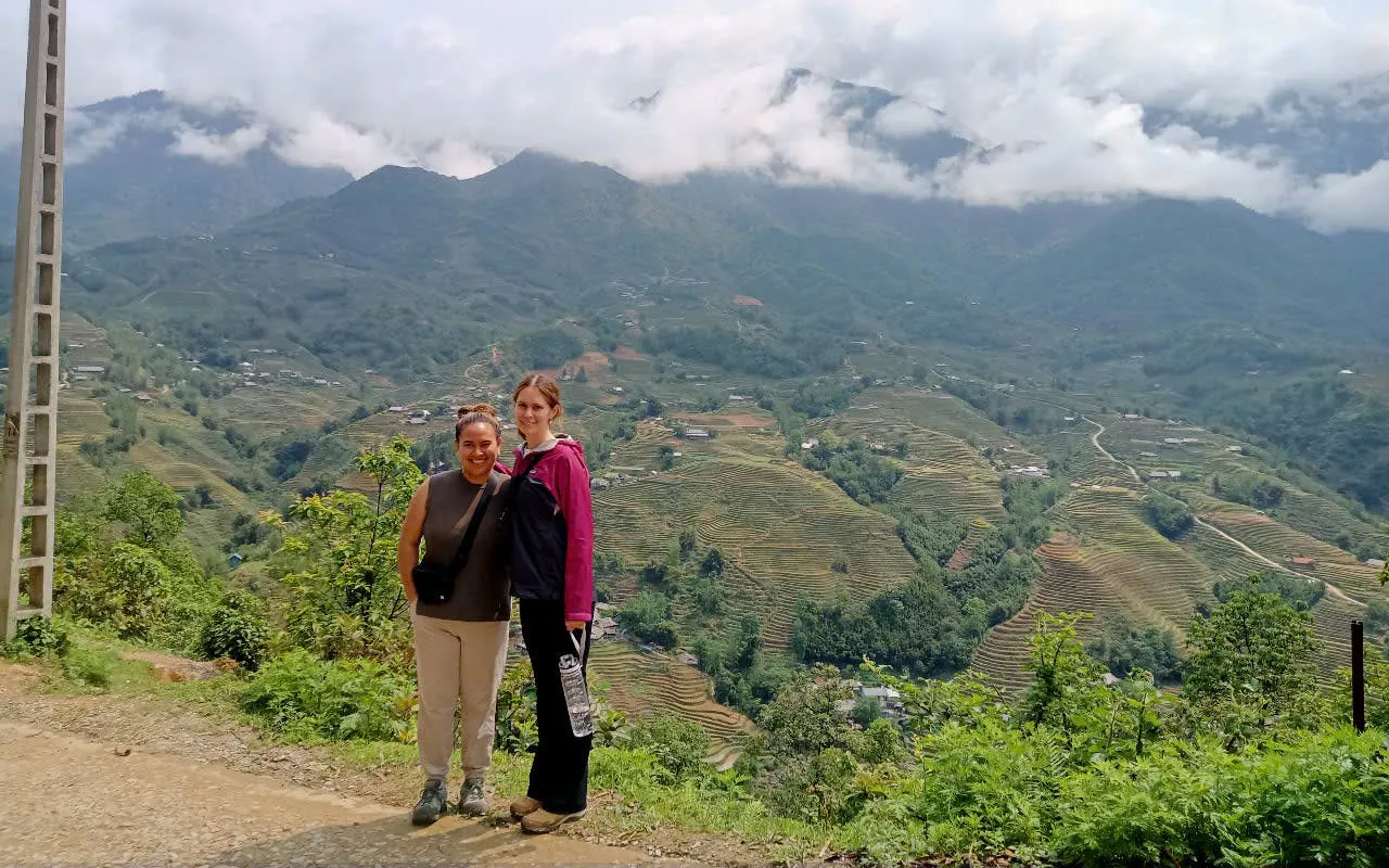 Tourists on a Sapa motorbike tour with terraced rice fields and mountains in the background.