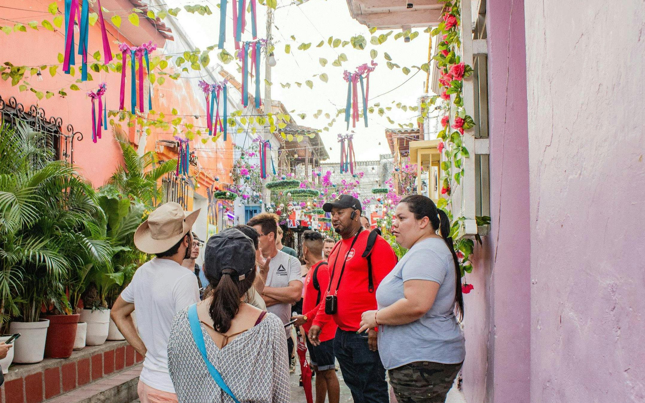 Tour group exploring vibrant alleyway in Getsemaní, Cartagena with colorful decorations.
