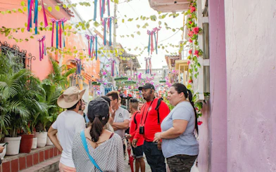 Tour group exploring vibrant alleyway in Getsemaní, Cartagena with colorful decorations.
