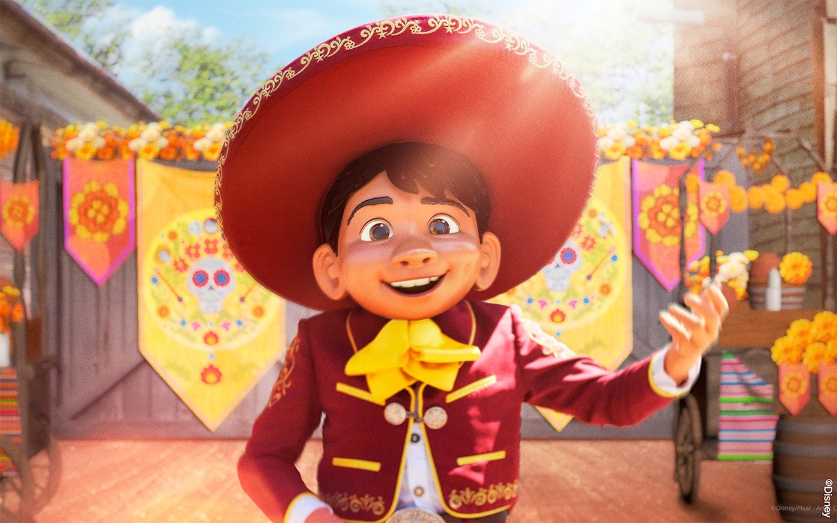 Character in traditional attire at Disneyland Paris with colorful decorations.