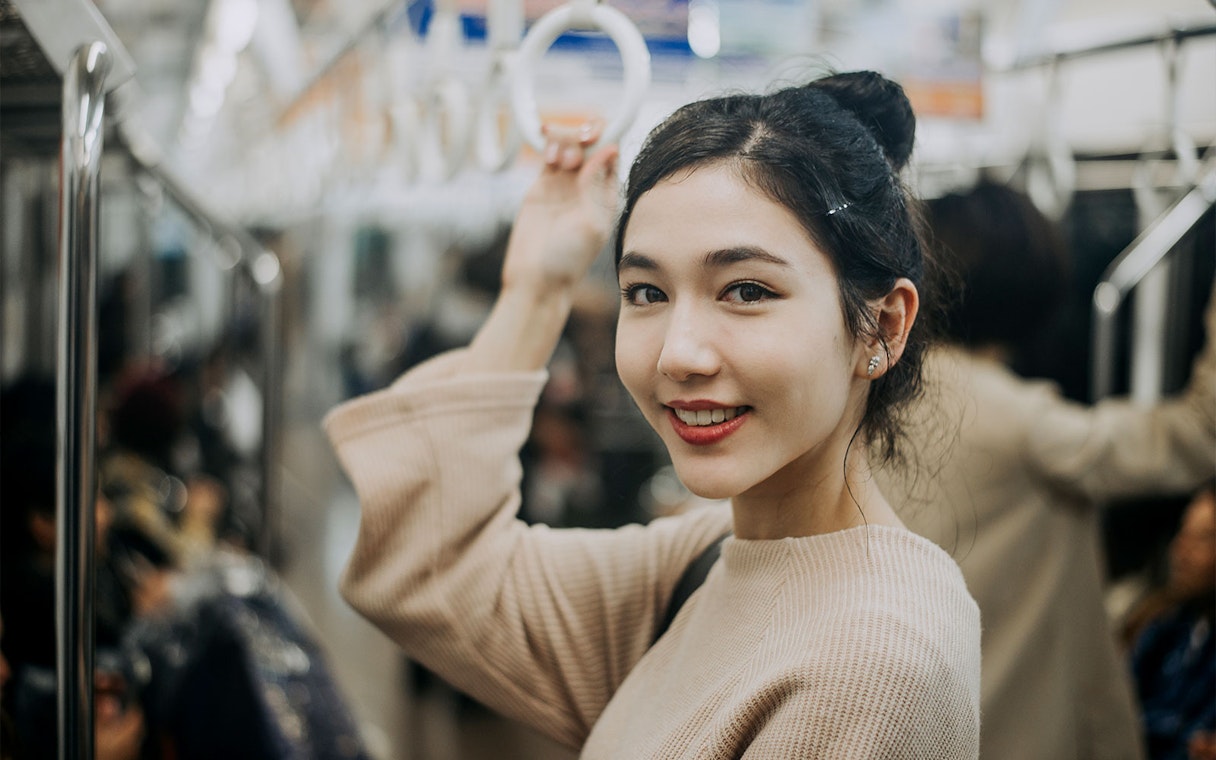 Woman holding onto a handrail in Tokyo subway.