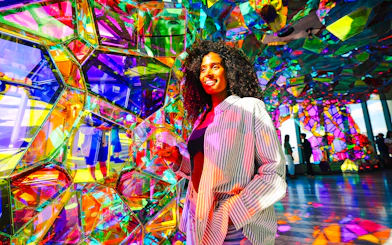Visitor enjoying colorful glass art installation at Edge NYC Observation Deck.