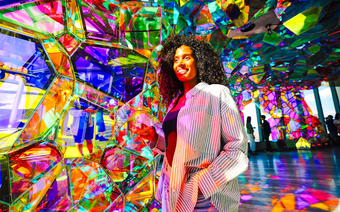 Visitor enjoying colorful glass art installation at Edge NYC Observation Deck.