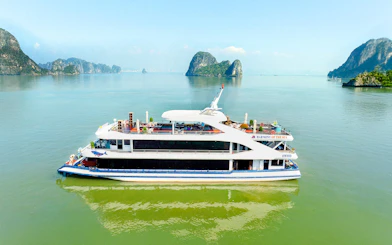 Harmony cruise ship sailing in Ha Long Bay with limestone islands in the background.