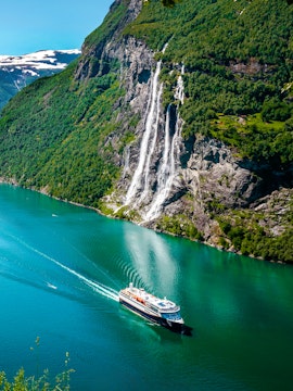 Cruise ship sailing past Seven Sisters waterfall in Geirangerfjord, Norway.