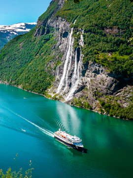 Cruise ship sailing past Seven Sisters waterfall in Geirangerfjord, Norway.