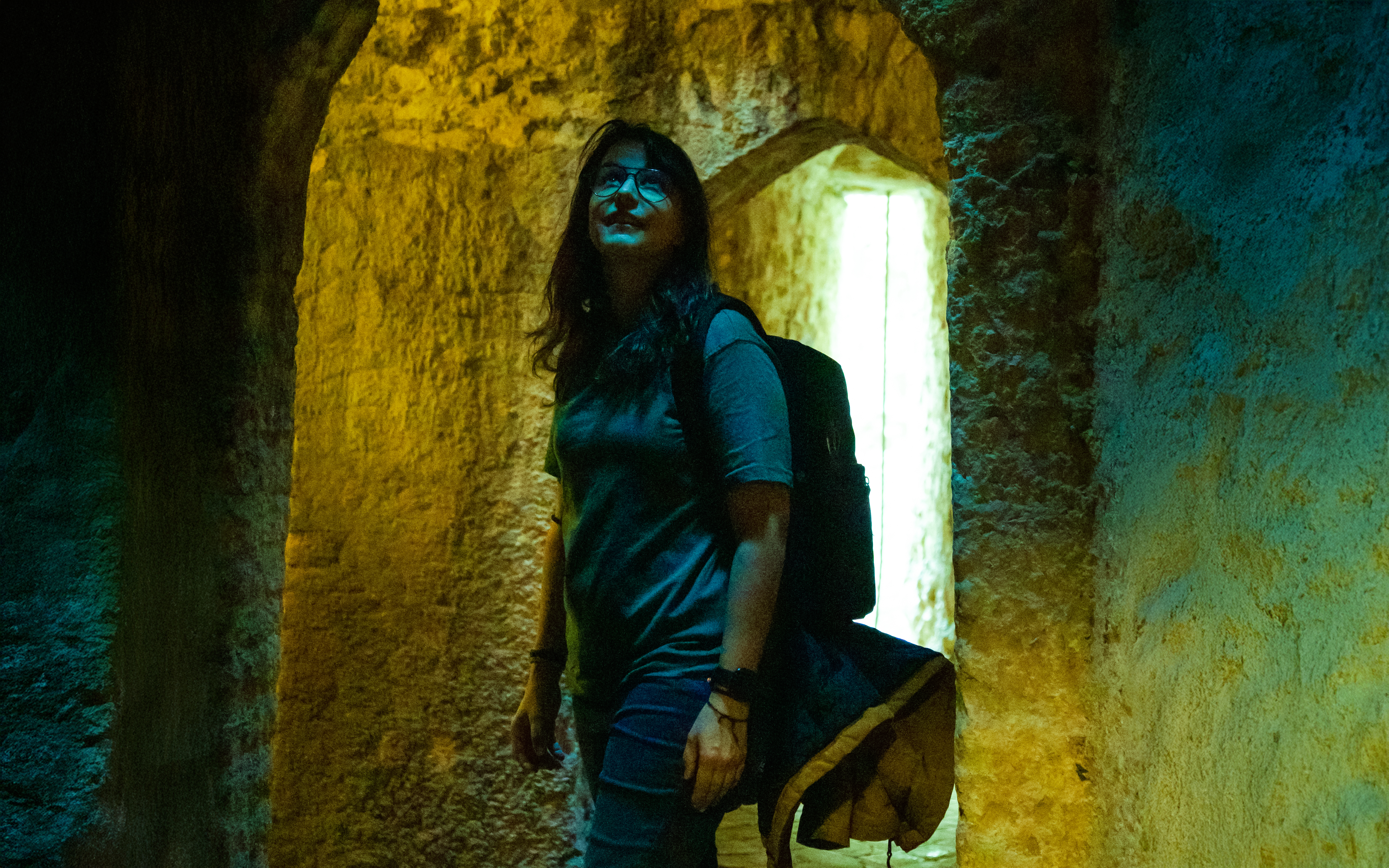 Woman exploring ancient stone vault with arched ceilings.