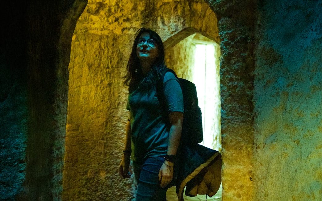 Woman exploring ancient stone vault with arched ceilings.