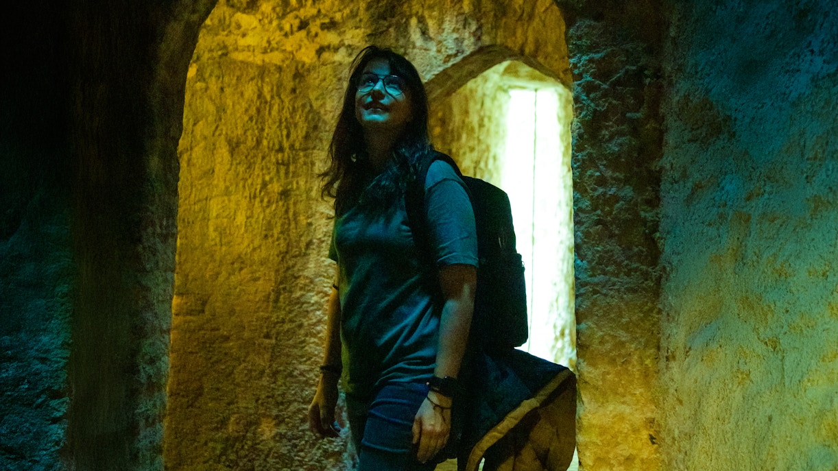 Woman exploring ancient stone vault with arched ceilings.