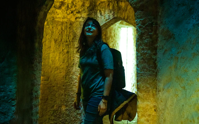 Woman exploring ancient stone vault with arched ceilings.