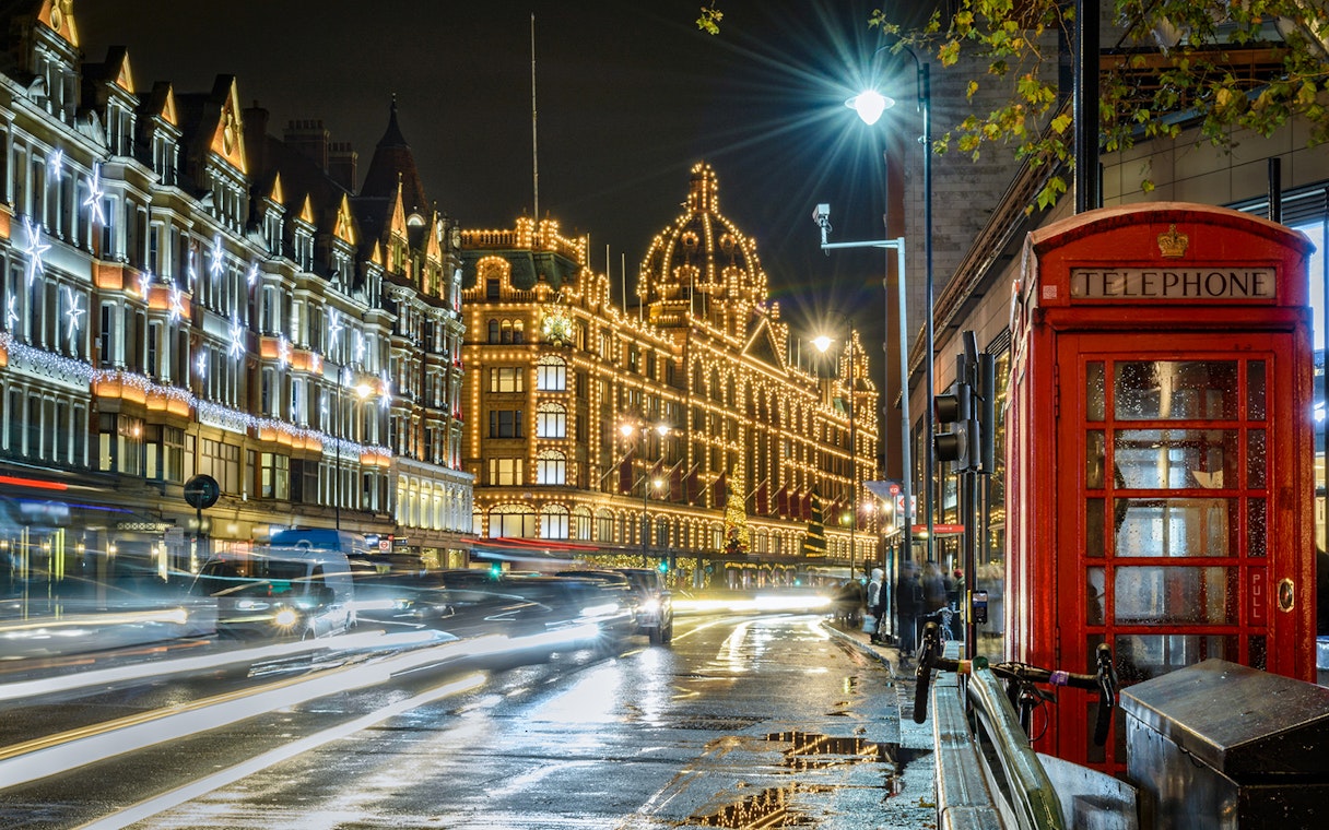 London street with Christmas lights, iconic red telephone booth, and illuminated buildings.