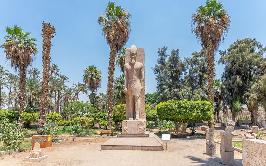 Statue of Ramses II surrounded by palm trees in Memphis, Egypt.