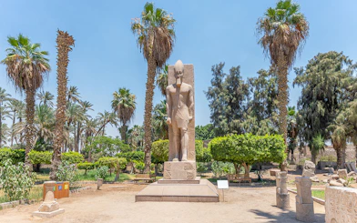 Statue of Ramses II surrounded by palm trees in Memphis, Egypt.