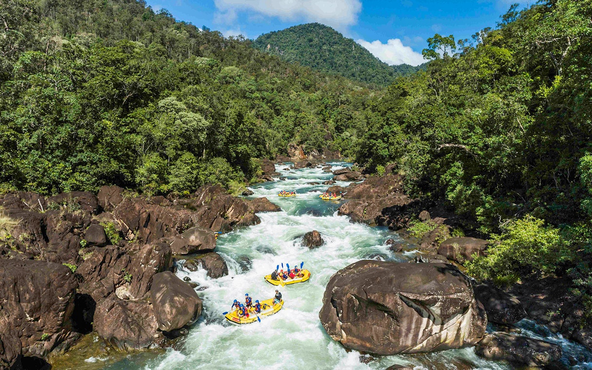 Rafting group navigating rapids on Barron River surrounded by lush forest.