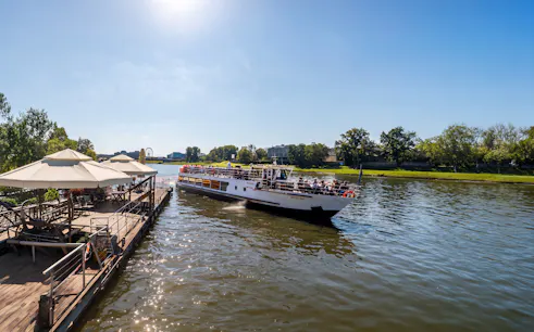 River cruise boat on the Vistula River in Krakow with passengers enjoying the view.