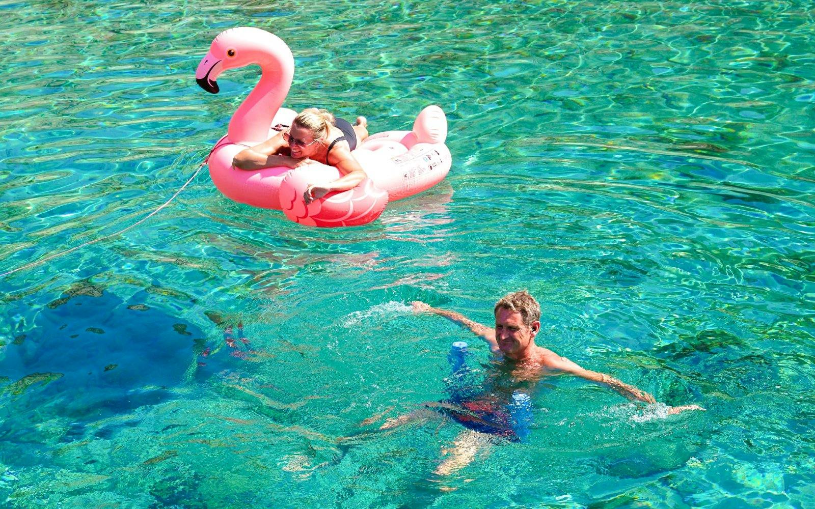 Guests swimming and relaxing on a pink float during a catamaran cruise from Ierapetra to Chrissi Island.