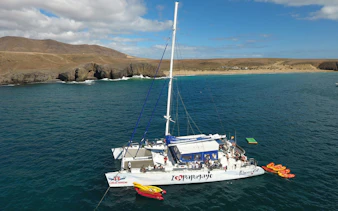 Catamaran near Papagayo Beaches, Lanzarote, with kayaks and tourists on board.