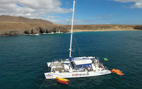 Catamaran near Papagayo Beaches, Lanzarote, with kayaks and tourists on board.