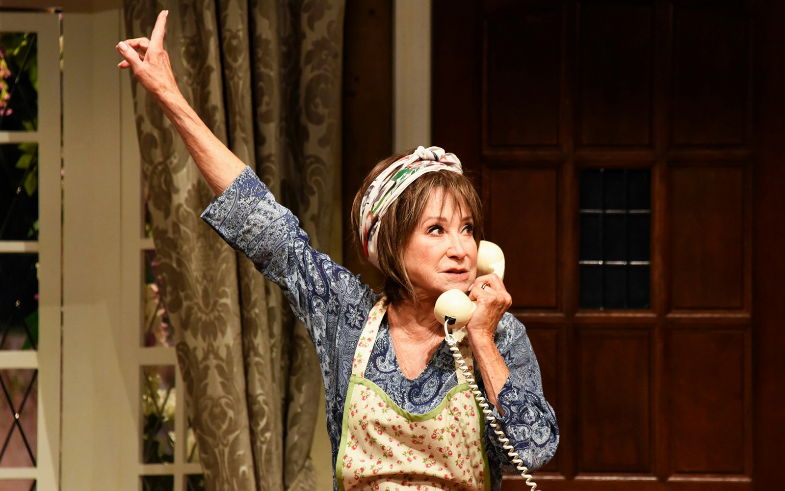 Woman on stage with phone during "Noises Off" performance.