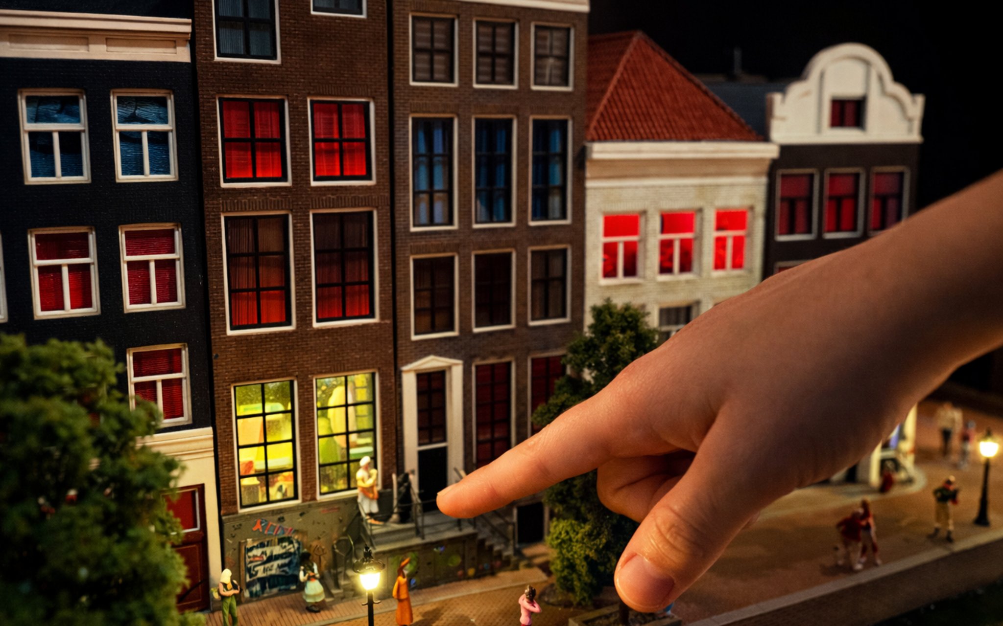 Miniature Amsterdam street scene with hand pointing at detailed buildings.